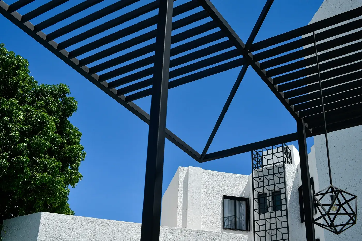 Pergola en aluminium noir à claire-voie, vue en contre-plongée sur ciel bleu